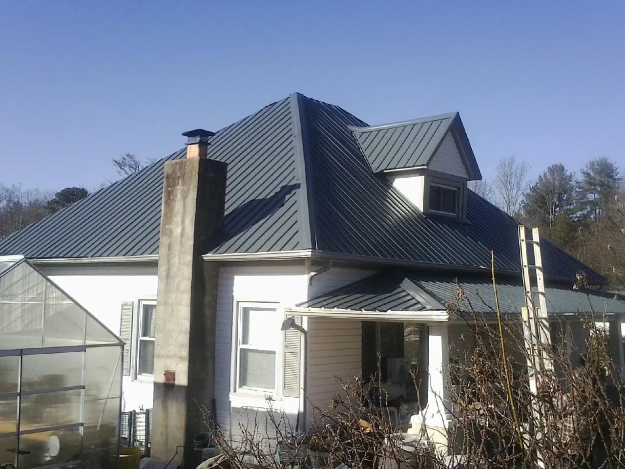 Dark blue standing seam metal roof on a white farmhouse with dormer — Slate & Tile Roof Repair by Roofing Brothers in Gamaliel