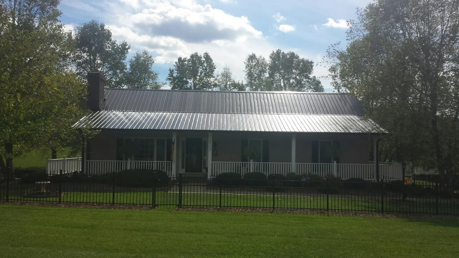 Gray metal roof on a brick ranch with a full width front porch — Gutter Guard Installation work by our crew in Gamaliel