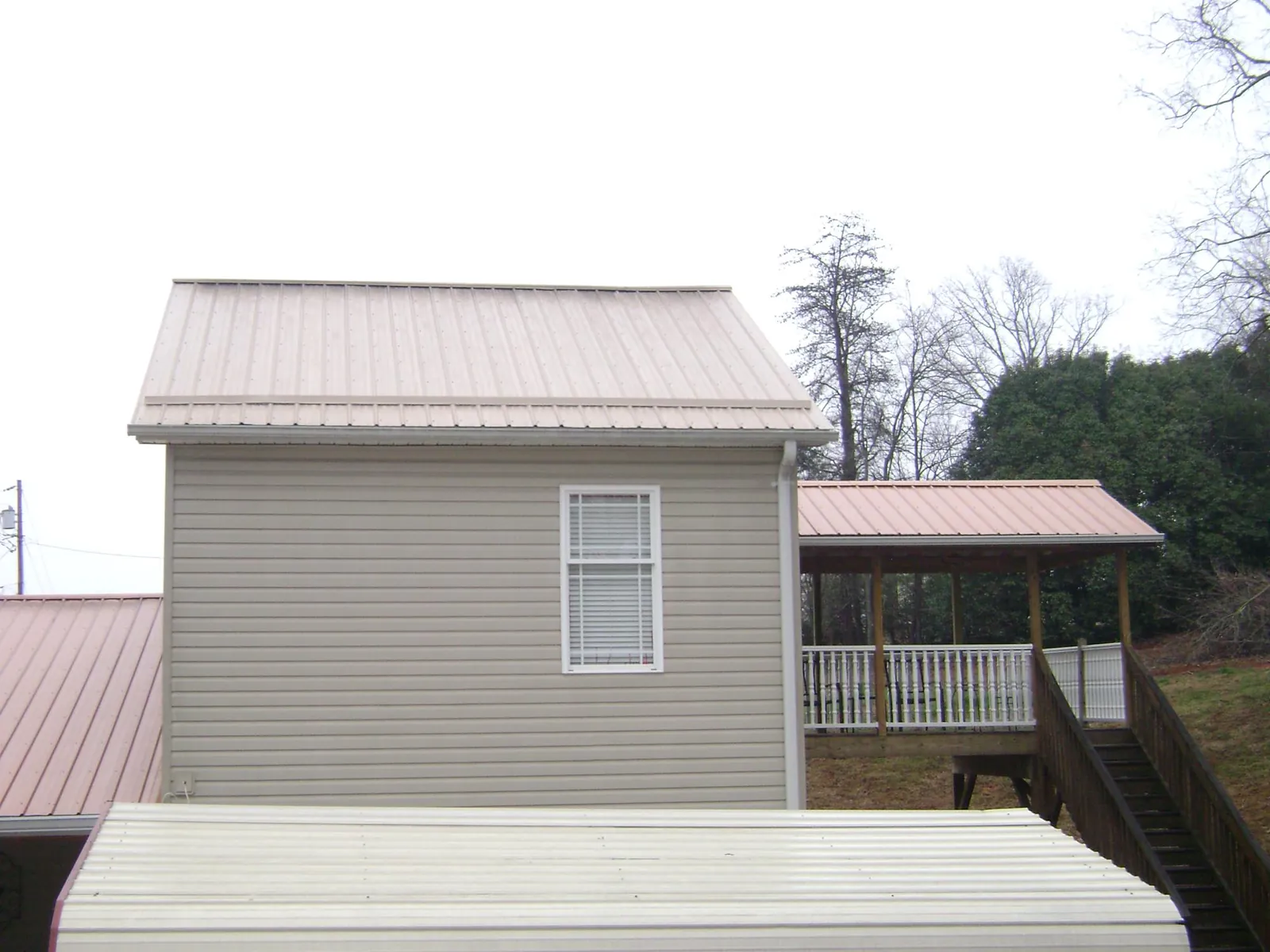 Tan metal roofs on a two story addition and attached porch, from a Roof Replacement job in Gamaliel